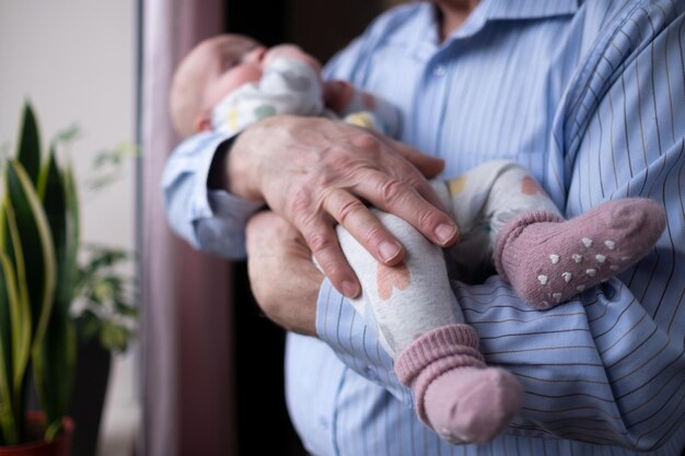 Grandfather holding a beautiful newborn baby girl at home