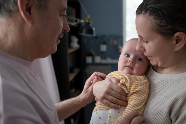 Grandfather looking on his granddaughter for first time playing with a newborn baby girl