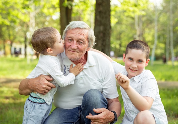 Дедушка играет с внуками. Мальчики обнимают своего дедушку