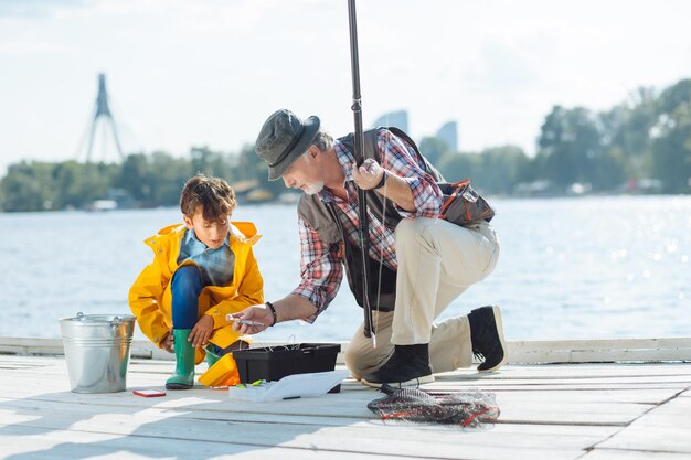 Grandfather showing fishing hooks to his grandson