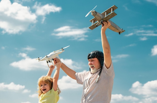 Grandfather and son with plane and quadcopter drone over blue sky and clouds background Men generation granddad and grandchild Elderly old relative with child