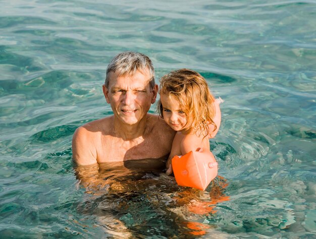 Фото Дедушка плавает с внучкой в озере.