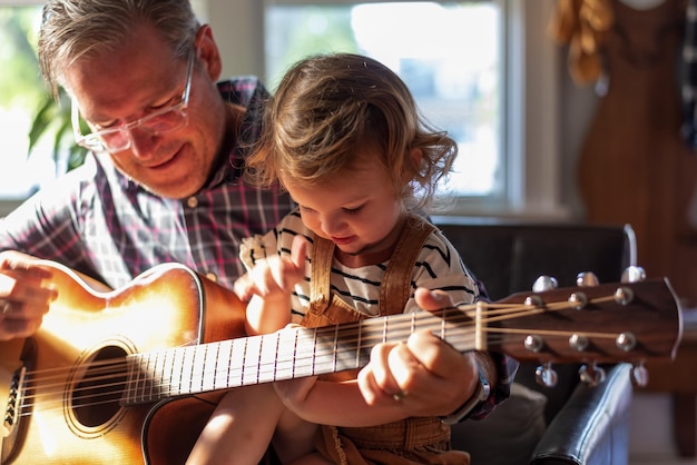 grandfather teaching guitar to daughter