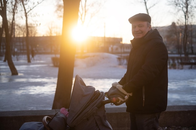 Grandfather walking with a baby stroller on snowy winter day