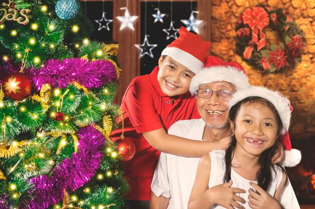 Grandfather with grandchildren near a Christmas tree