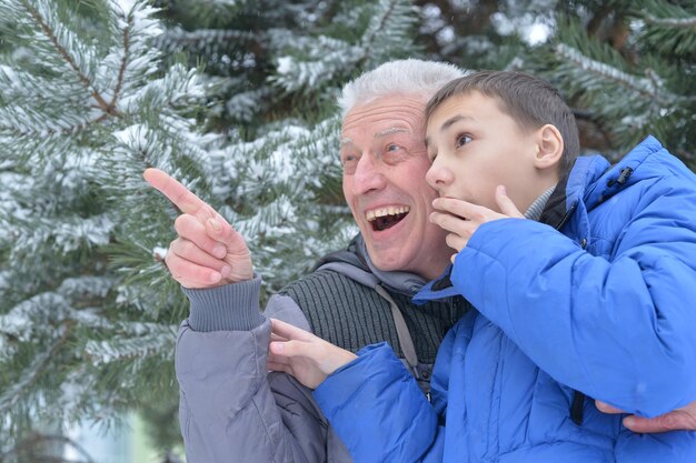 Grandfather with grandson together, posing outdoors in winter