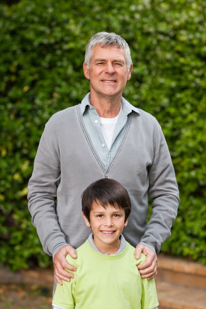 Grandfather with his grandson looking at the camera in the garden 