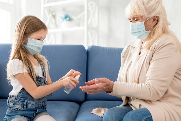 Nonna e ragazza con maschera con disinfettante