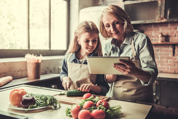 Grandma and granddaughter are using a digital tablet.