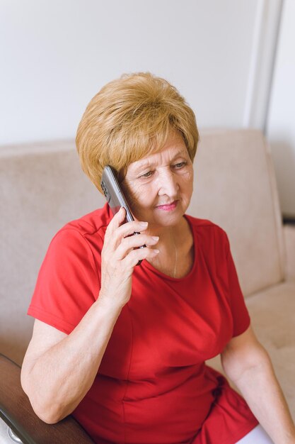 Grandma is talking on the phone and smiling Sweet elderly woman holding the phone in her hand