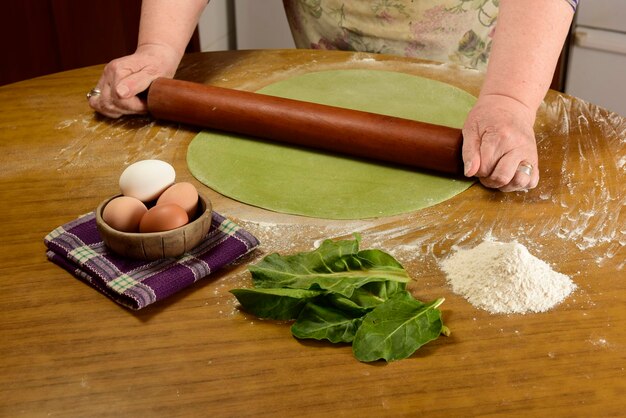 Photo grandma's hands kneading dough for green noodles