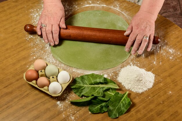 Foto le mani della nonna che impastano la pasta per le tagliatelle verdi