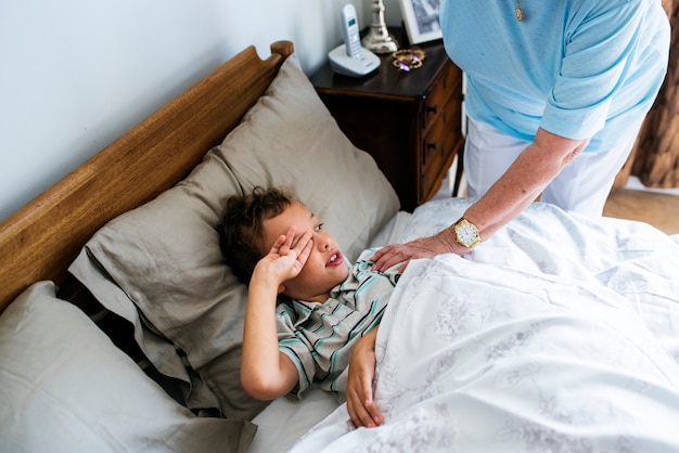 Photo grandma waking her grandson up from the bed