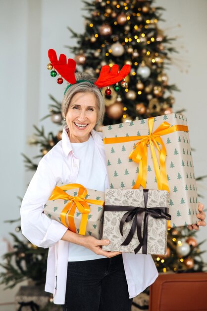 Nonna che indossa il cappello di natale dei cervi regali di natale nelle mani