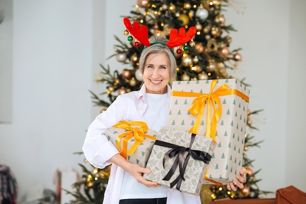 鹿のクリスマス帽子をかぶったおばあちゃんクリスマスプレゼントを手に