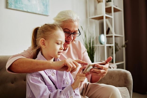 Nonna con la bambina che usa lo smartphone