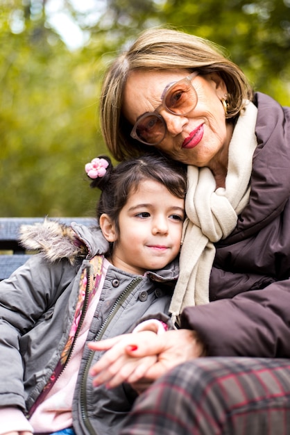 Grandmother and child sitting on the bench in the autumn park