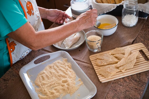 Grandmother cooking at home fish - indoor at the kitchen - retired senior - arms and hands in the photo