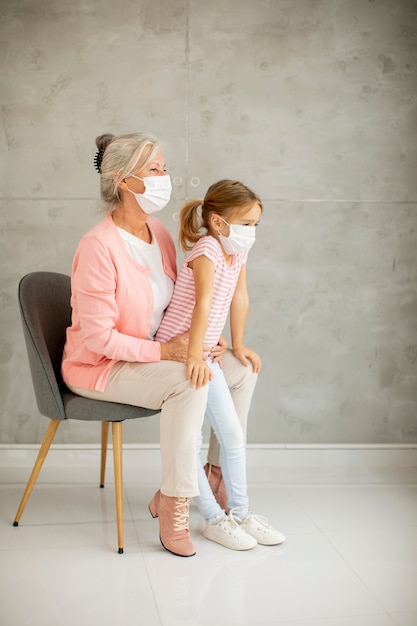 Grandmother and cute little granddaughter wearing a respiratory masks