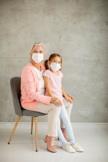 Grandmother and cute little granddaughter wearing a respiratory masks