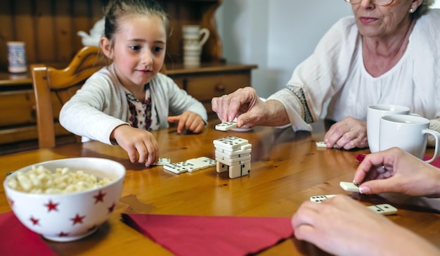 Grandmother daughter and granddaughter playing with dominoes in the living room