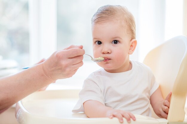 Grandmother gives baby food from a spoon