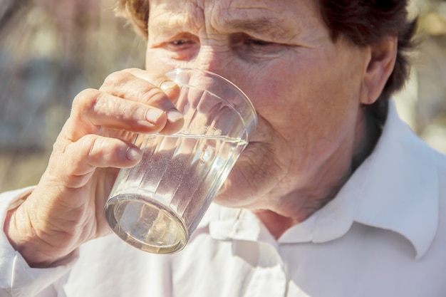 Foto nonna che dà un bicchiere di acqua pulita a un bambino. messa a fuoco selettiva