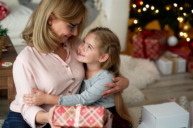 Grandmother giving her little granddaughter a Christmas gift