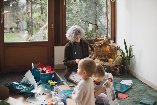 Grandmother and grandchildren open gifts for a christmas