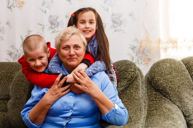 Grandmother and grandchildren sitting together on sofa in living room