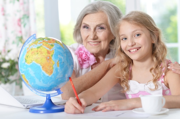 Grandmother and granddaughter doing homework at home together