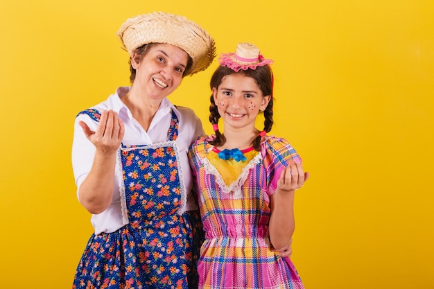 Grandmother and granddaughter dressed in typical Festa Junina clothes Calling with the hands inviting come here