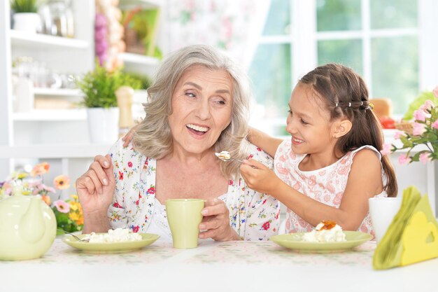 Grandmother and granddaughter having breakfast together in kitchen