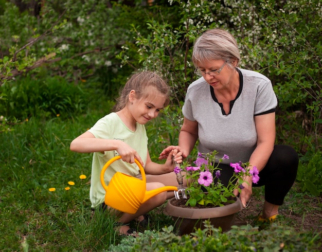 Foto nonna e nipote che piantano fiori nel giardino in una giornata estiva