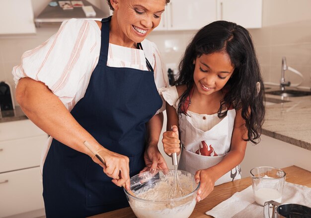 Photo grandmother and granddaughter prepare dough together in the kitchen