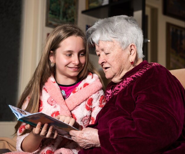 Nonna e nipote che leggono un libro a casa