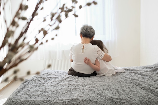 Photo grandmother and granddaughter sit back and hug.