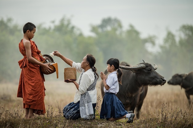 Grandmother and grandson offer food to the novices