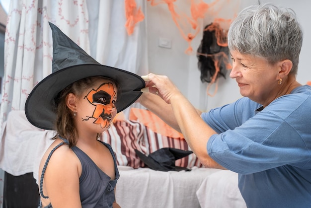 Бабушка помогает девочке надеть костюм на Хэллоуин.