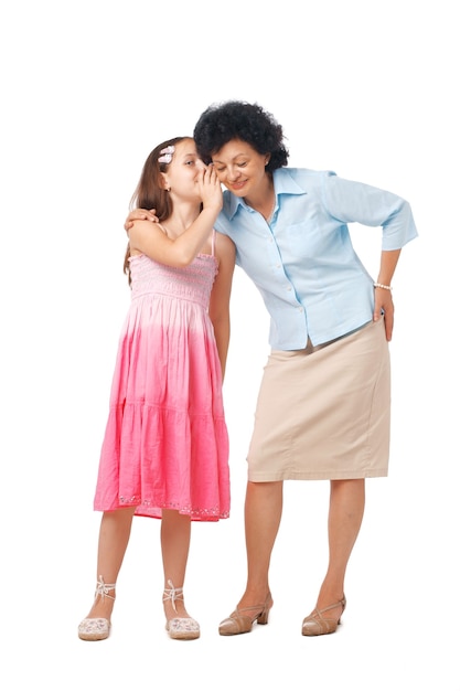 Grandmother and her grand daughter whispering something into her ear, full length