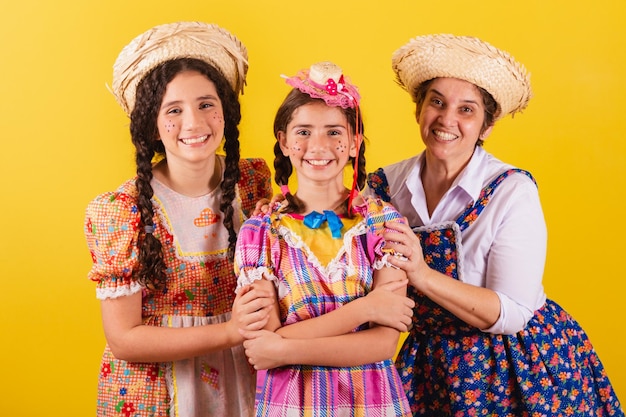 Grandmother and her two granddaughters dressed in typical Festa Junina clothes Hugging and smiling