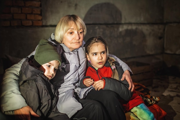 Фото Бабушка обнимает маленьких украинских детей, они пережидают атаку российского агрессора в бомбоубежище