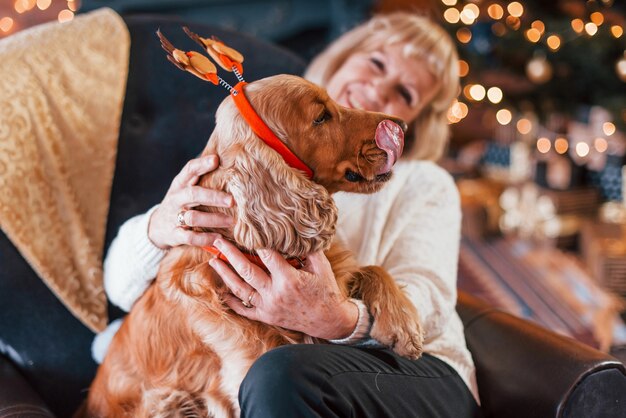 Grandmother indoors with dog in christmas decorated room.