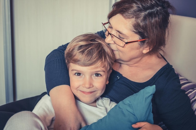 Photo grandmother kissing grandson on bed