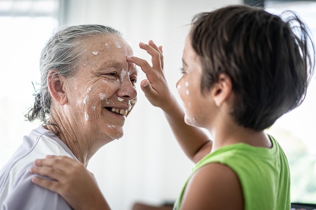Grandmother and little boy putting cream protection on their face
