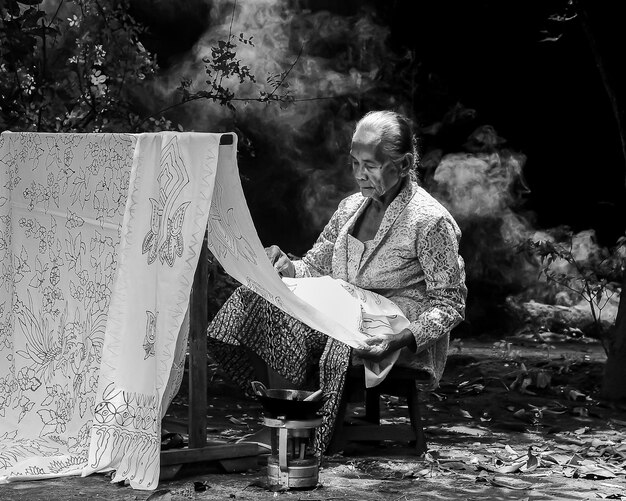 Photo a grandmother making batik cloth