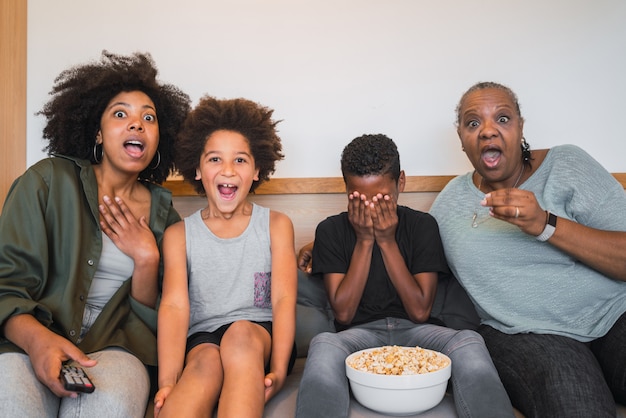 Grandmother, mother and children watching a movie at home.