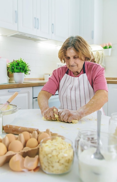 Grandmother old woman in the kitchen bakes prepares the dough in the kitchen Selective focus Food