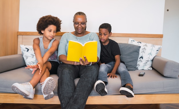 Grandmother reading a book to grandchildren.