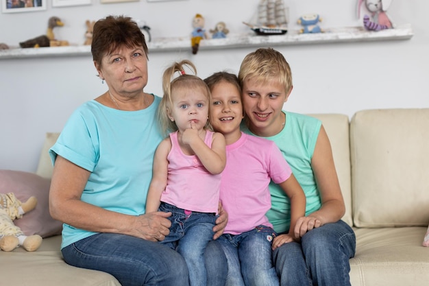 Grandmother sits with grandchildren on the couch at home